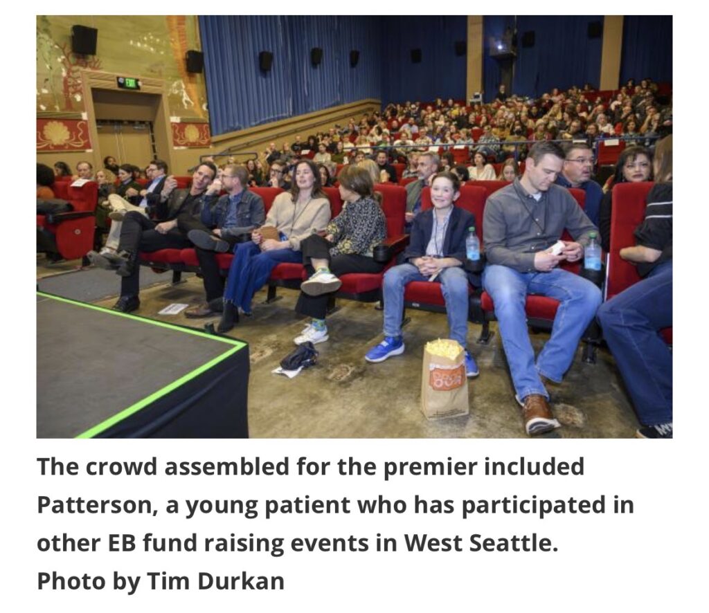 Audience members seated in a theater during a film premiere, with Patterson sitting among them.